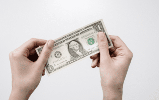 Two hands holding a dollar