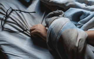Arm in bed with glasses